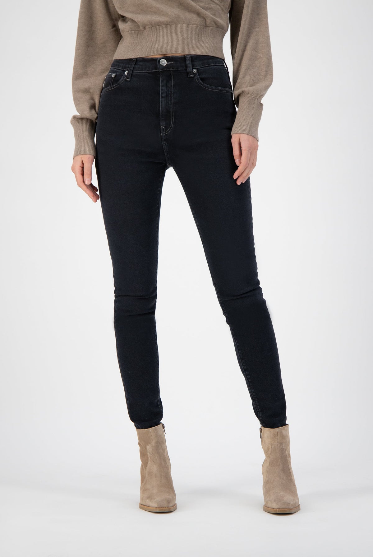 High-waisted black denim jeans paired with neutral beige ankle boots and a beige sweater, showcasing casual chic style.