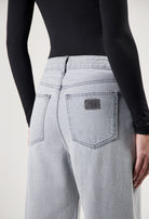 Light gray high-waisted denim jeans with wide-cut legs, paired with a fitted black long-sleeve top.