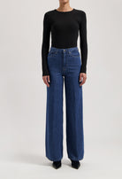 A stylish outfit featuring high-waisted, wide-leg blue jeans paired with a fitted, long-sleeve black top.