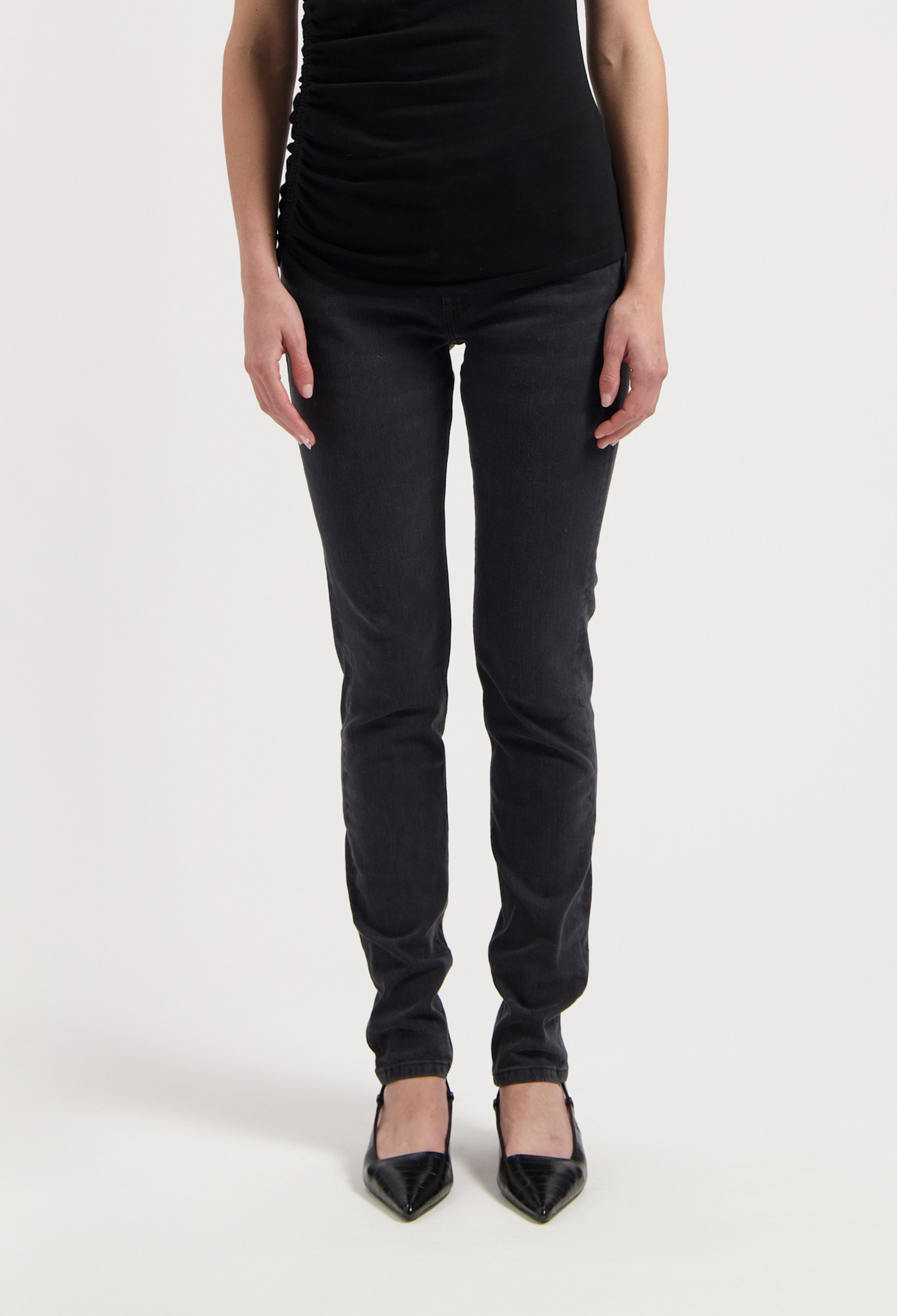 Chic black slim-fit pants paired with a sleeveless top and pointed black heels on white background, highlighting stylish casual wear.