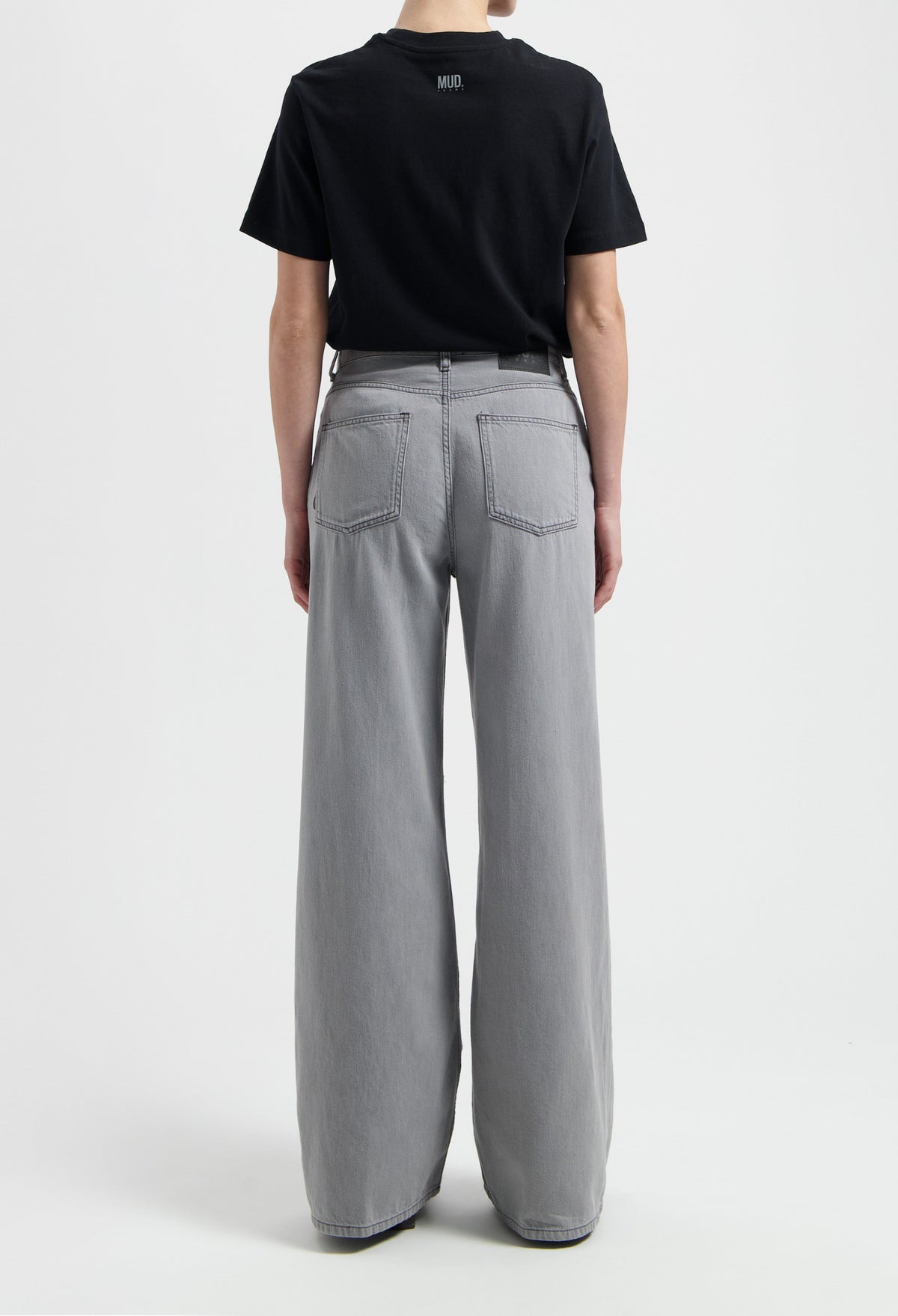 Sustainable MUD Jeans in beige, crafted from organic cotton, offering a tailored fit, paired with a gray T-shirt.